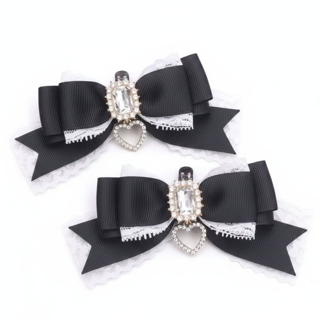 Two black ribbon hair bows with white lace trim and a central rhinestone heart charm, displayed on a beige lace background with small red heart accents.